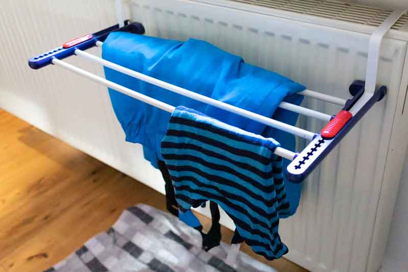 Nasse Kleidung trocknet auf einem Trockenständer an der Heizung